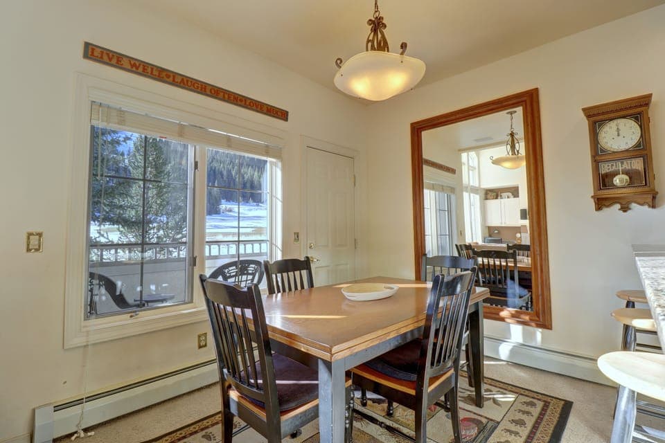 A dining room with a wooden table and chairs. A large window offers an outdoor view of ski slopes.