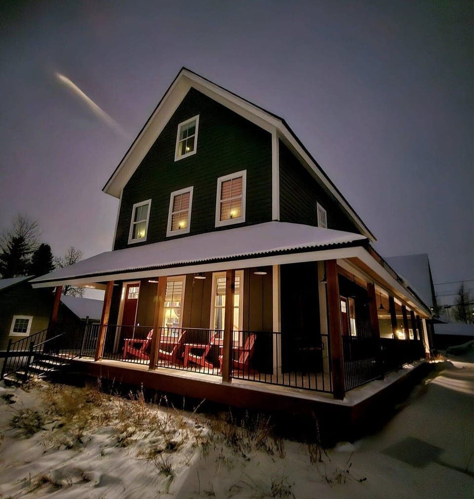 Shooting star at dusk with warm light glowing from inside the house.