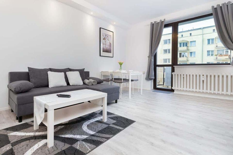 The bright interior of the living room leads out onto the balcony. Plenty of natural light streams in through the glass door and large window.
