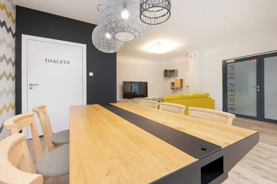 A bright dining space with a wooden table, black chairs, and modern lighting fixtures.