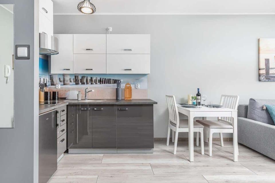 A sleek, modern kitchenette featuring gray cabinets, white countertops, and stainless-steel appliances.