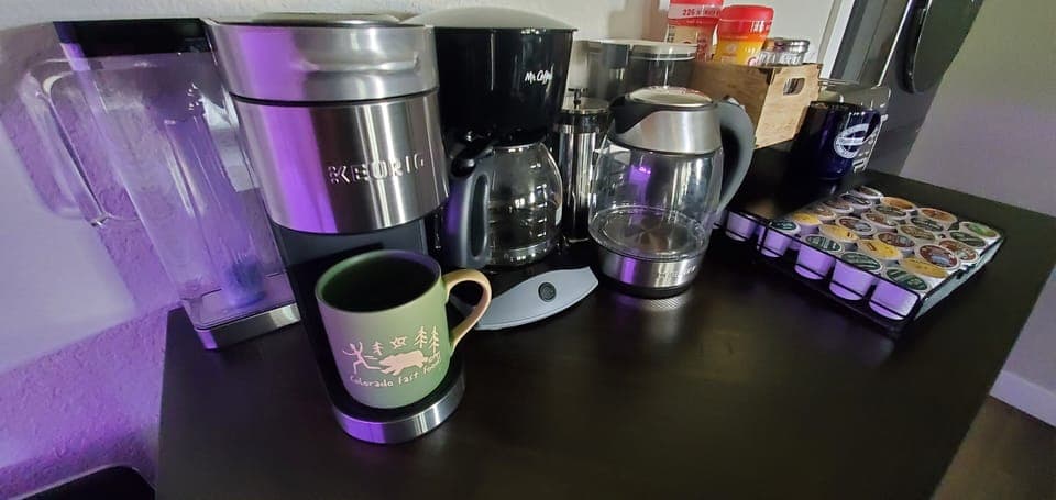 Hot drinks bar w/ variety of coffee pods + decaf, hot cocoa, tea, creamers.