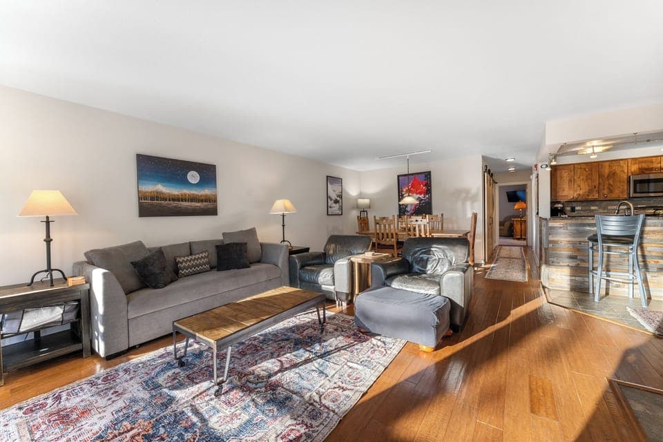 Spacious living area with wood-burning fireplace, ample seating, queen sized sleeper sofa, hardwood flooring and flat screen TV.