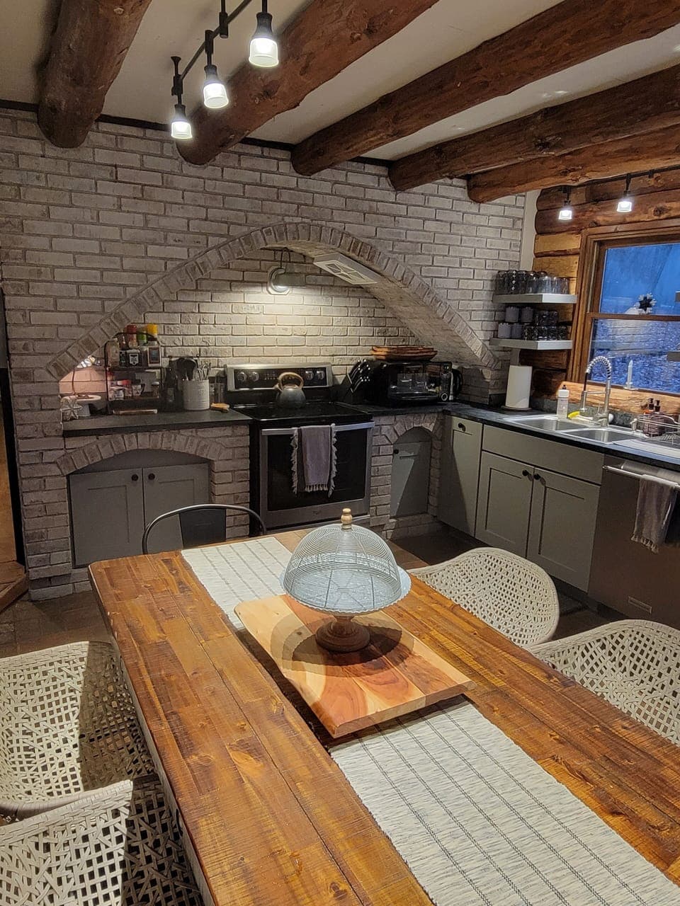 The brick floor and accent wall adds to the charm of this open kitchen