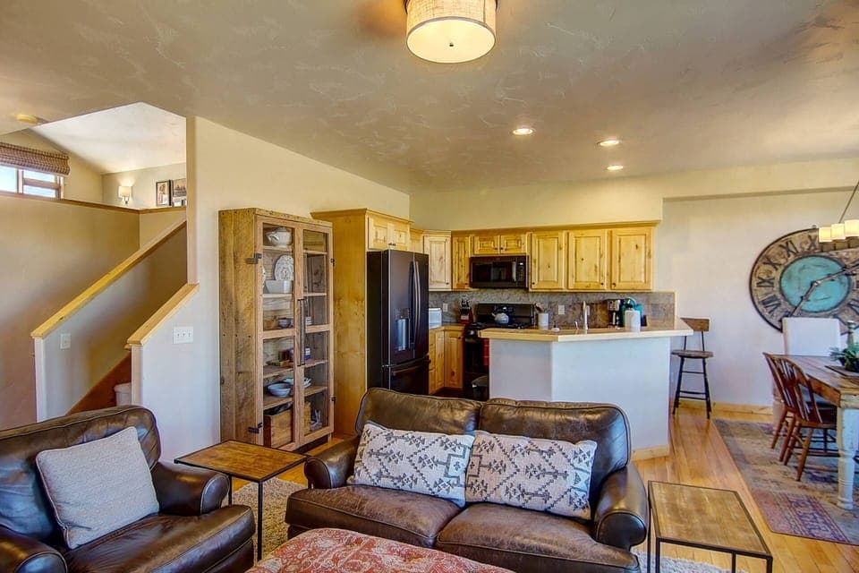 Warm and inviting open-concept living area featuring rich leather seating, rustic wood finishes, and a fully equipped kitchen—perfect for relaxing eve
