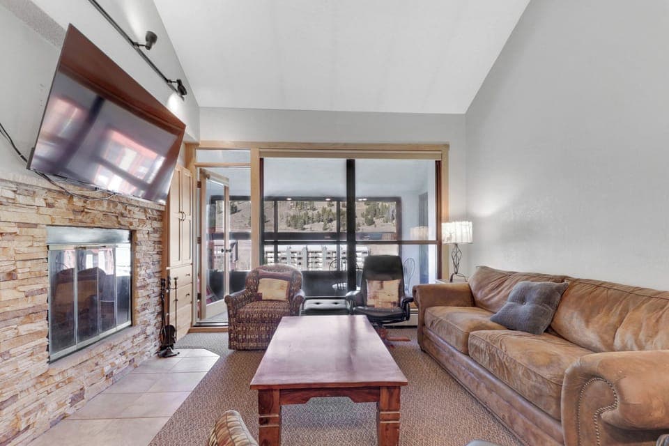 Sink into the plush leather sofa by your cozy stone fireplace while enjoying stunning mountain views through floor-to-ceiling windows. The perfect spot to unwind after your adventures.