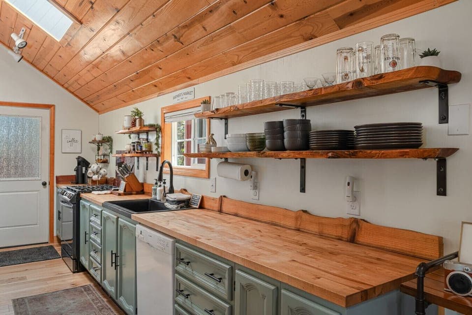 Enjoy cooking in a bright, rustic kitchen featuring open shelving, warm wood accents, and everything you need for a comfortable stay.