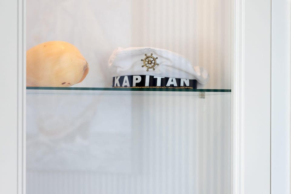 A decorative  captain's hat displayed on a white shelf.
