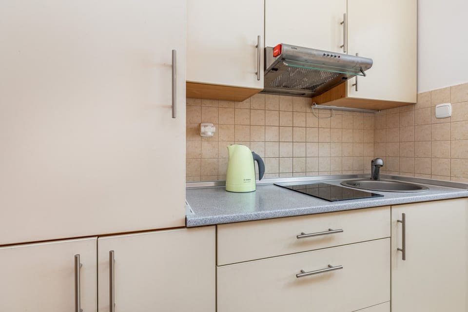 A compact, functional kitchen with light-colored cabinets and essential appliances, perfect for preparing meals in a cozy space.