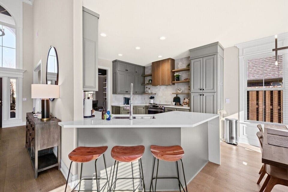 Here, you'll see a bar area with three wooden barstools looking into the kitchen.