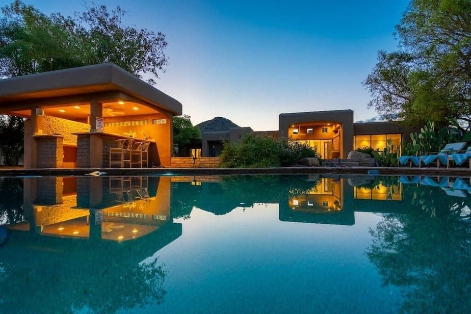 Relax by the illuminated outdoor pool and bar area at sunset in this southwestern-style retreat.