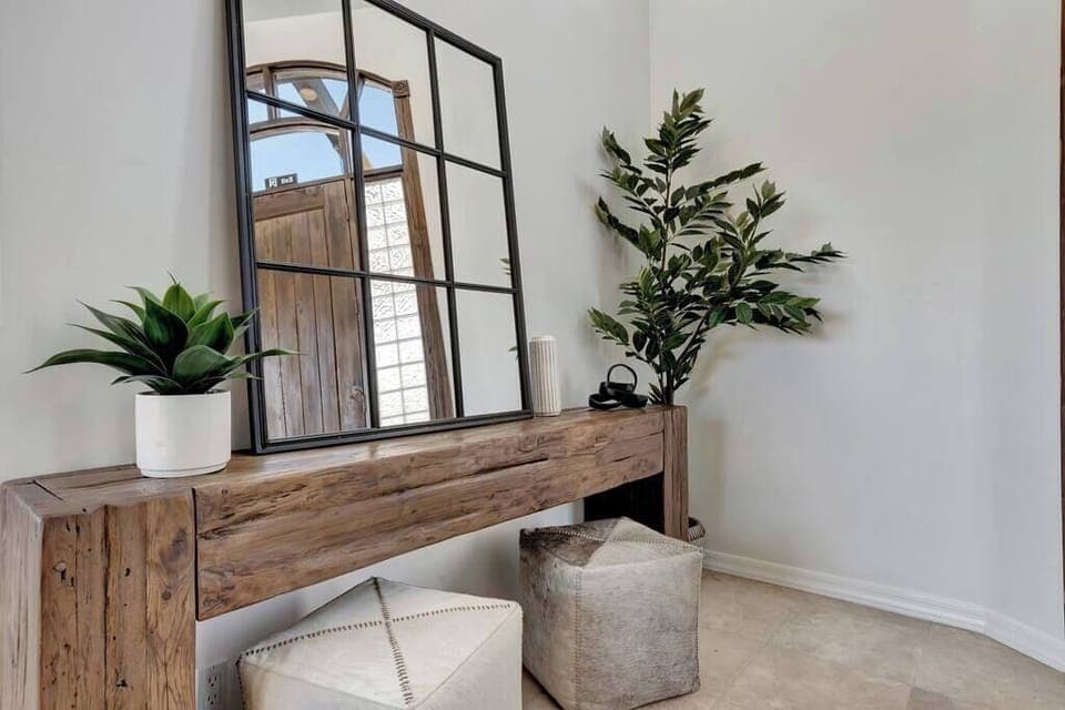 rustic wooden console table with a large grid mirror and decorative plants in a bright corner