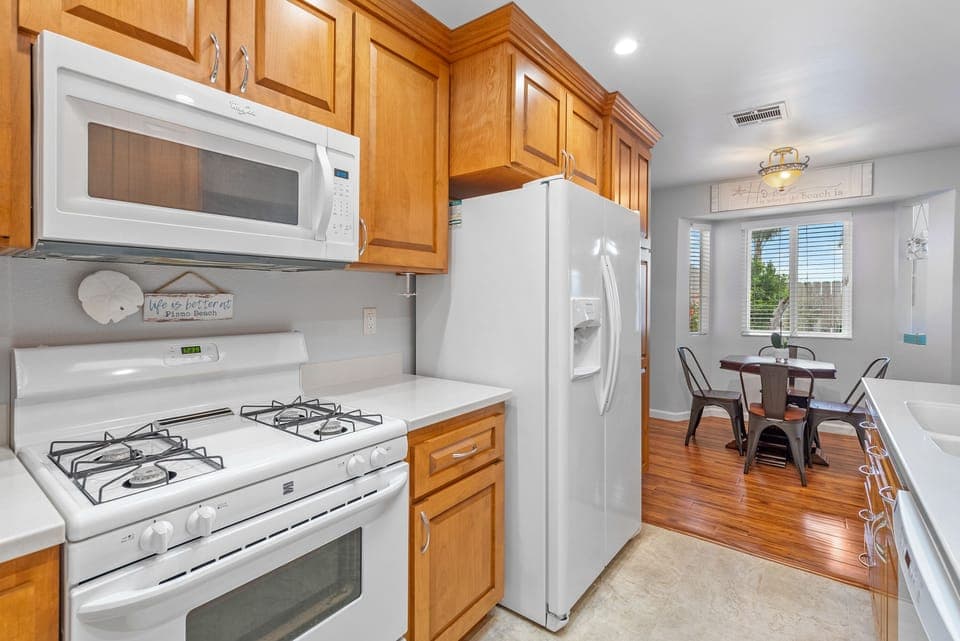 Kitchen with chef grade appliances. The kitchen is stocked with cookware, dinnerware and glasses.