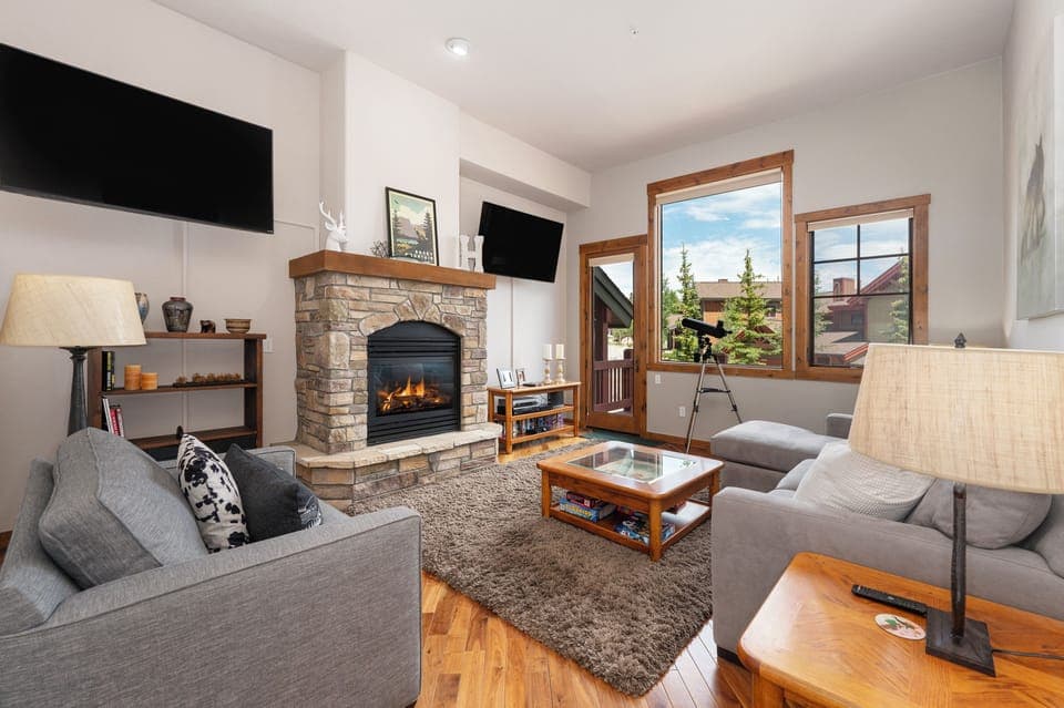 - Bright and inviting living space with a stone fireplace and soft, plush seating - Large windows showcase scenic views and let in glowing natural light - Cozy up indoors or stargaze from the telescope by the window nook