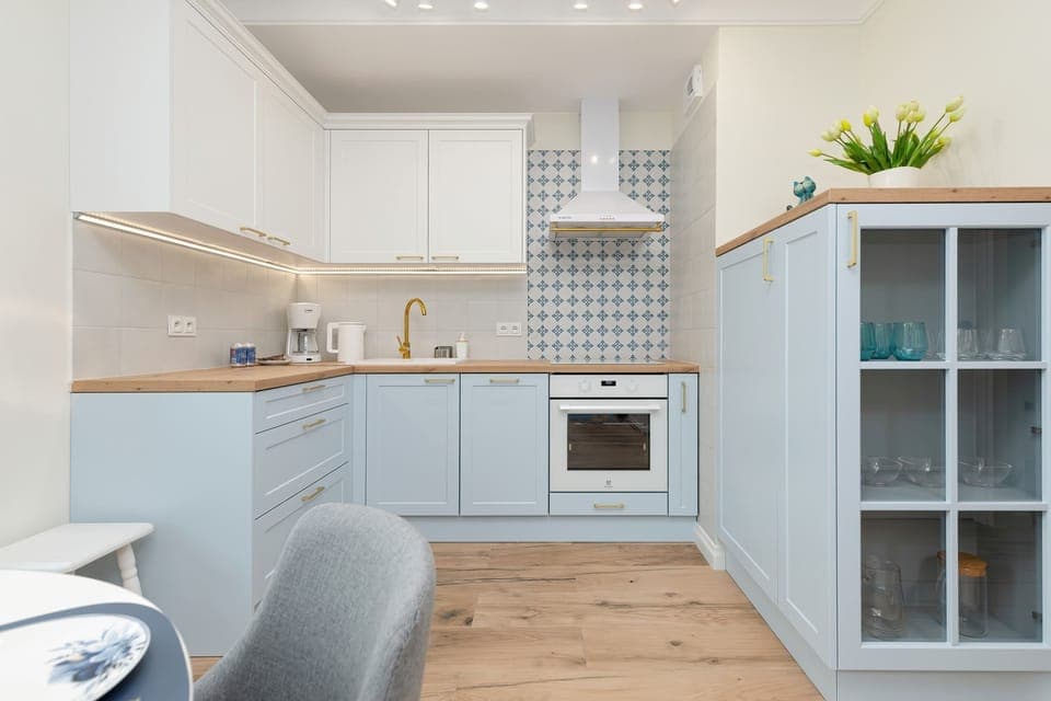 Open kitchen with white cabinets, wooden details, and a functional layout.
