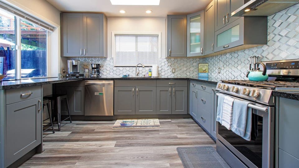 Stainless appointed kitchen with island, gas stove, side by side refrigerator.