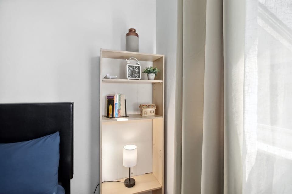 "Cozy bedroom with a comfortable queen bed, soft lighting, and ample natural light from large windows. Perfect for a restful night’s sleep."