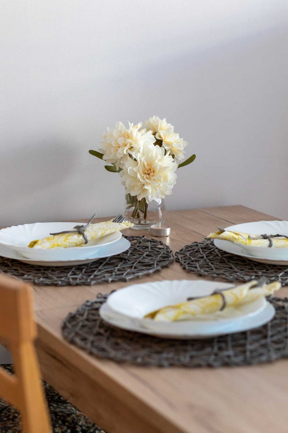  A close-up of a table setting with a vase of flowers, elegant tableware, and folded napkins