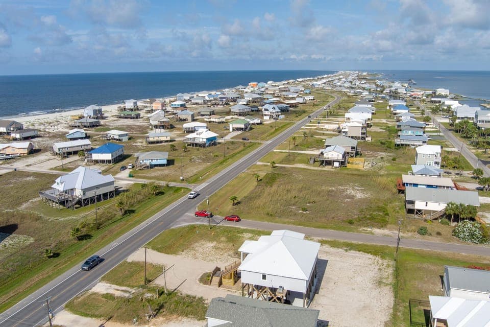 Aerial view of a charming coastal community with beach houses scattered across the shoreline, offering easy access to pristine beaches.