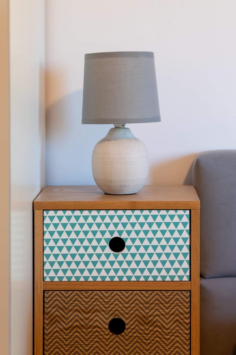 The nightstand next to the bed features a modern design with a lamp and a small storage compartment for essentials, creating a functional and stylish piece of furniture.