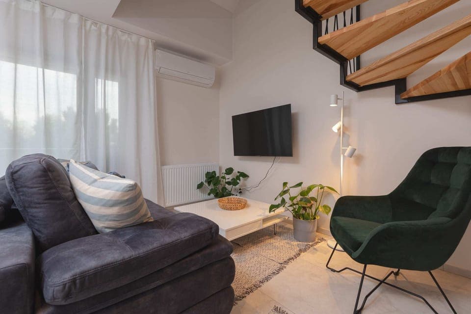 Air-conditioned, bright living room with a sofa bed and TV.