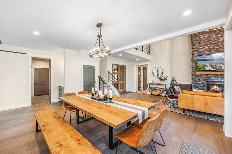 Modern lodge dining with seating for ten, soaring ceilings, and a cozy stone gas fireplace.