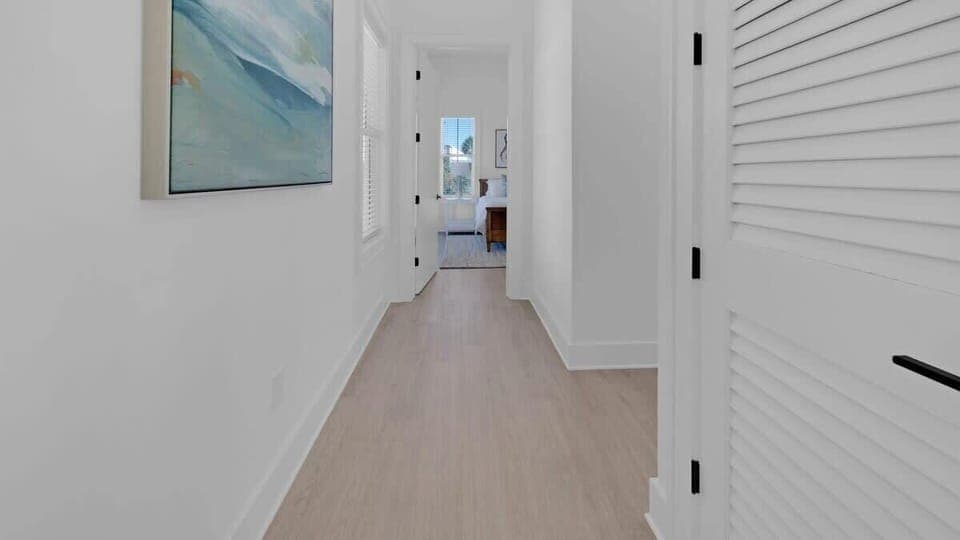 Hallway to first floor primary bedroom, powder room, and laundry room 