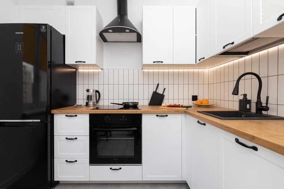 Fully equipped kitchen featuring black and white cabinetry, wooden countertops, and modern appliances.
