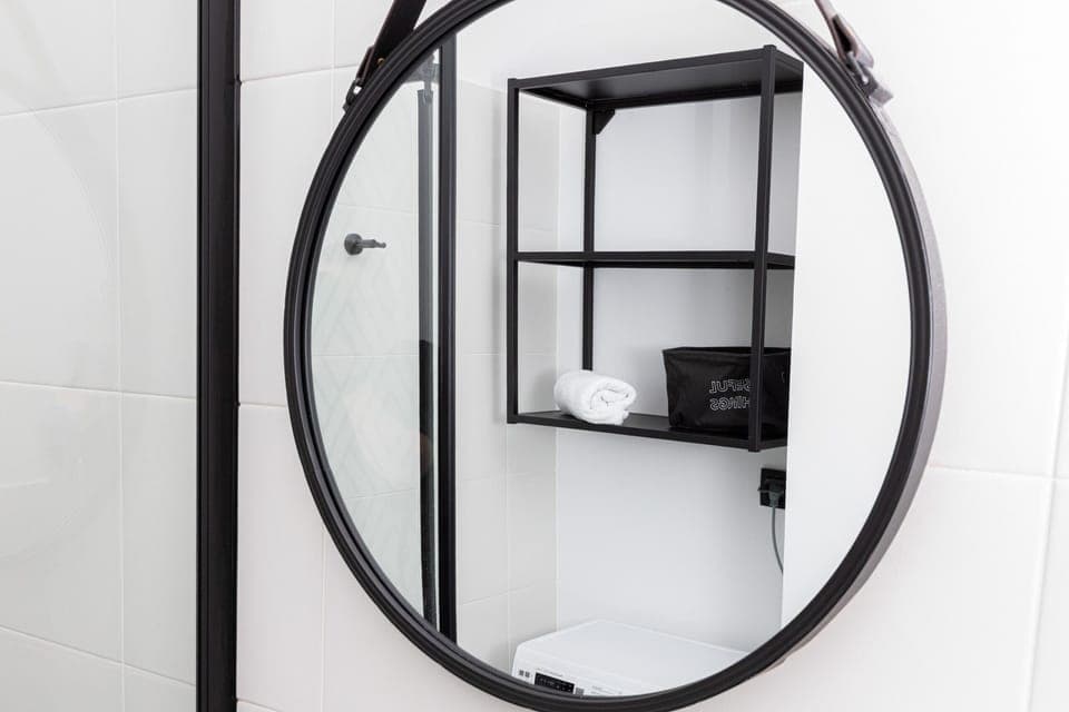 Circular bathroom mirror with black framing, adding a modern touch to the decor.
