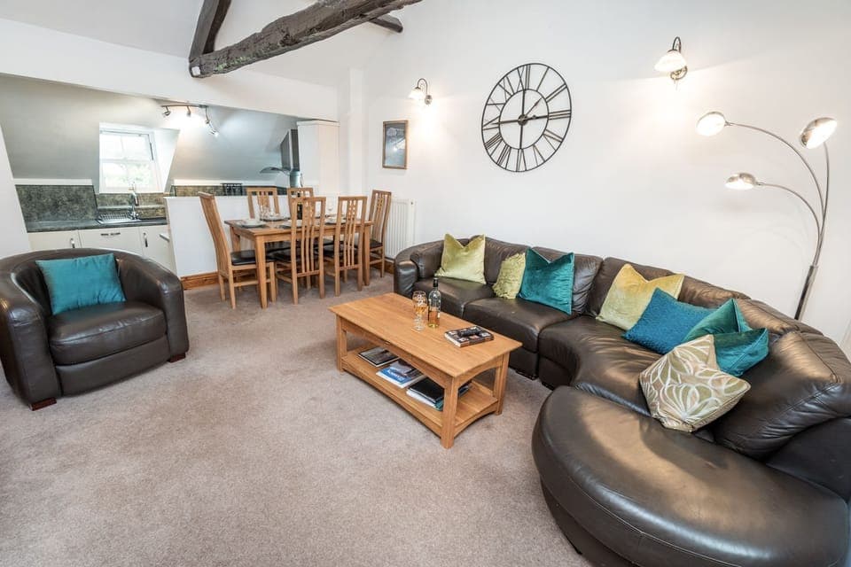 The living area features a large leather corner sofa and two armchairs