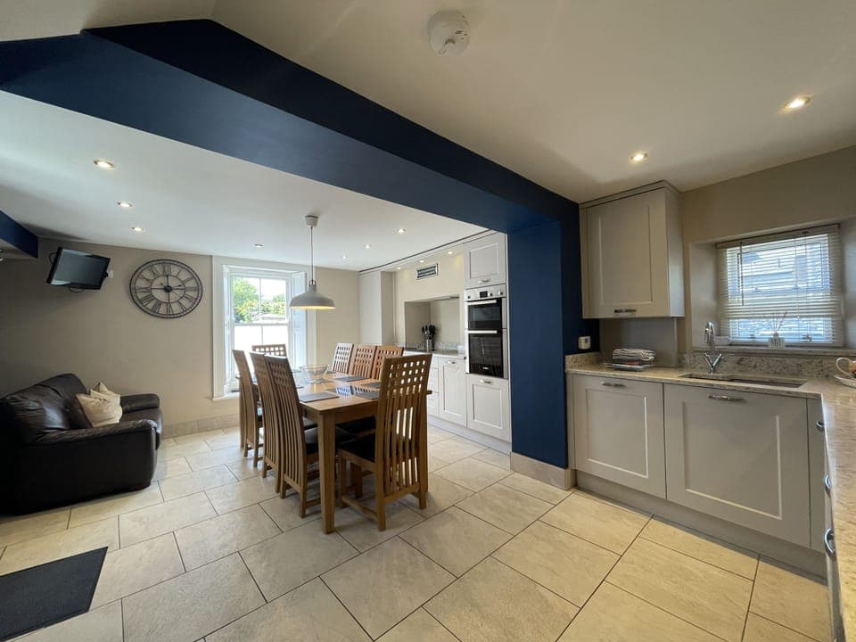 The kitchen area is equipped with Bosch integrated appliances including induction hob, quartz worktop, Tassimo coffee machine, and large dining table and chairs