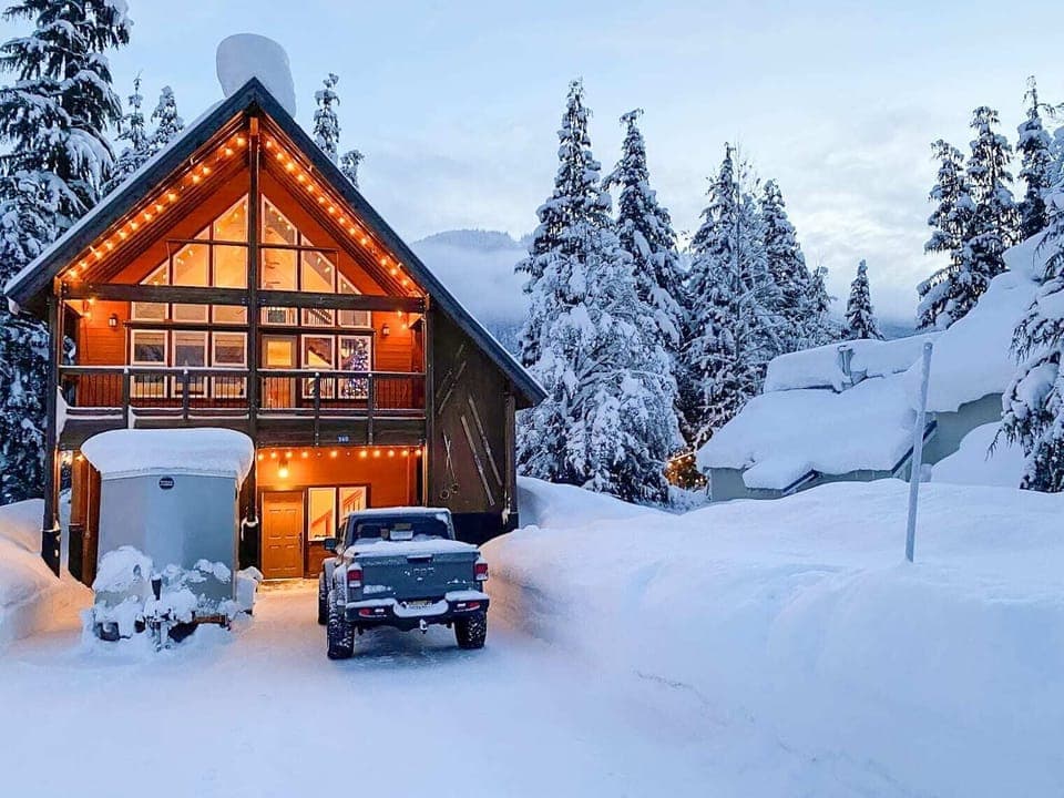 Cozy mountain chalet with warm lighting amidst a winter wonderland setting.