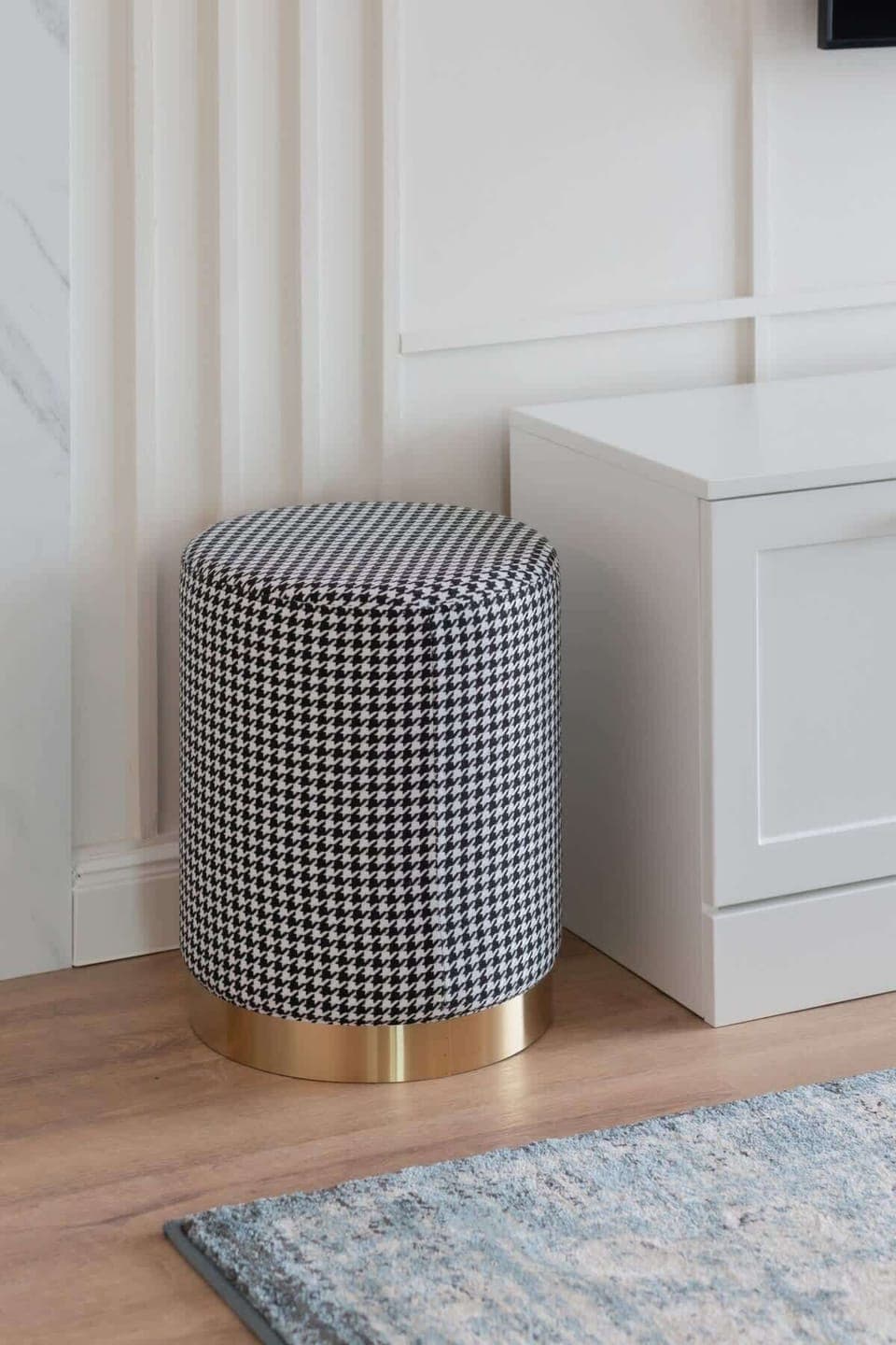 A small, stylish pouf in a neutral tone, adding functionality and comfort to the living space.