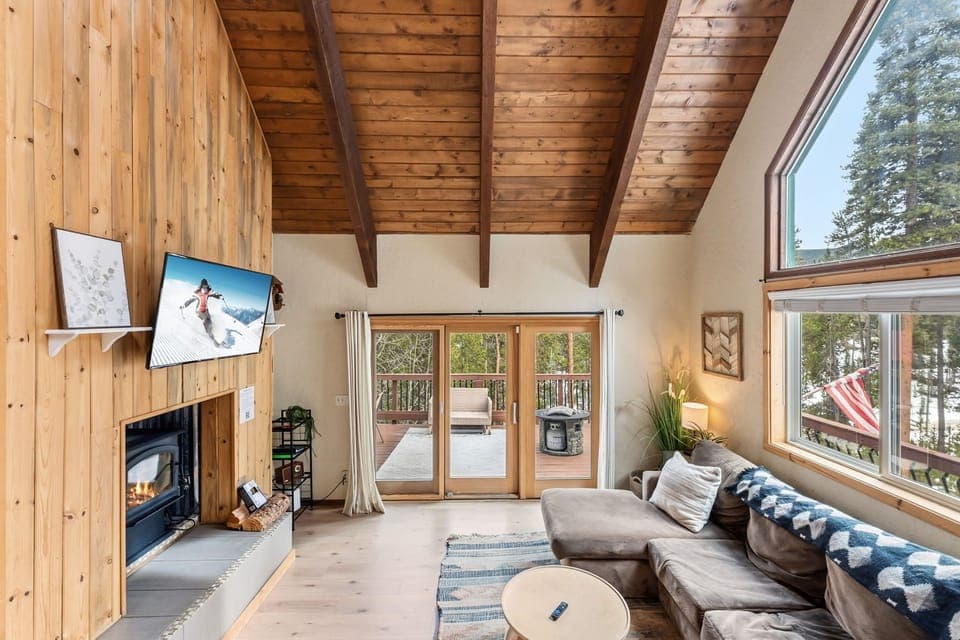 Cozy up by the crackling fireplace in this rustic living room with vaulted ceilings and mountain views from every window.