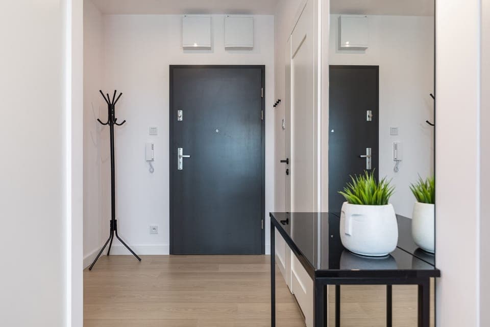 An entrance hallway with modern furniture, a decorative plant, and a clean design.
