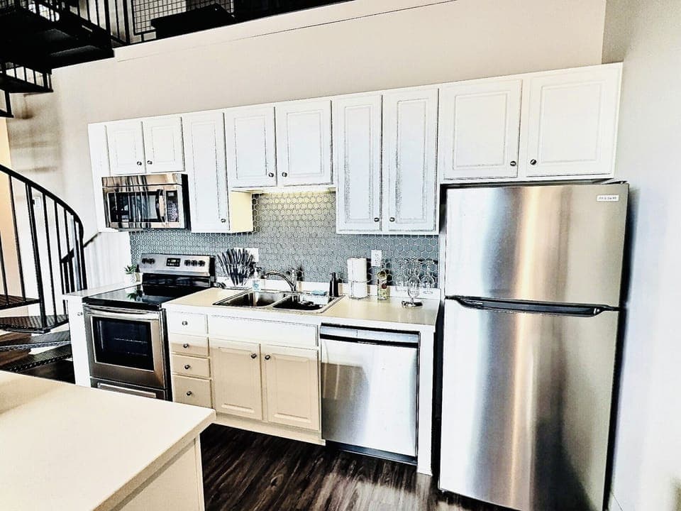 Fully equipped kitchen with modern appliances, island seating, and open loft above. Perfect for cooking, gathering, and entertaining.