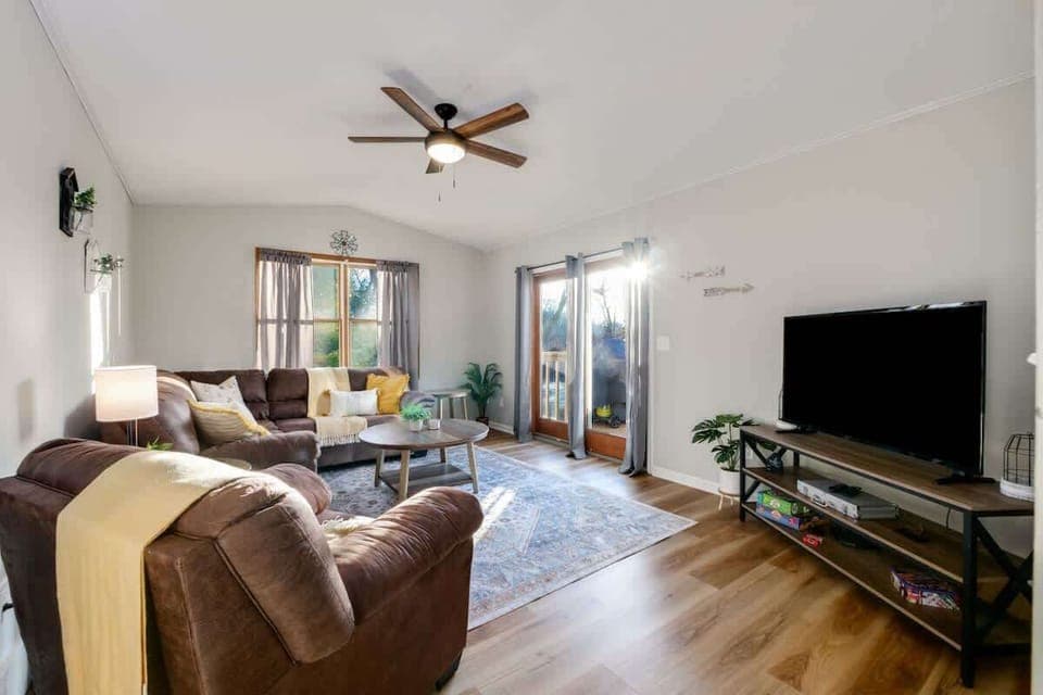 - Bright living room with large windows and natural light   - Cozy sectional seating with TV for family entertainment   - Easy access to outdoor deck with peaceful water views  