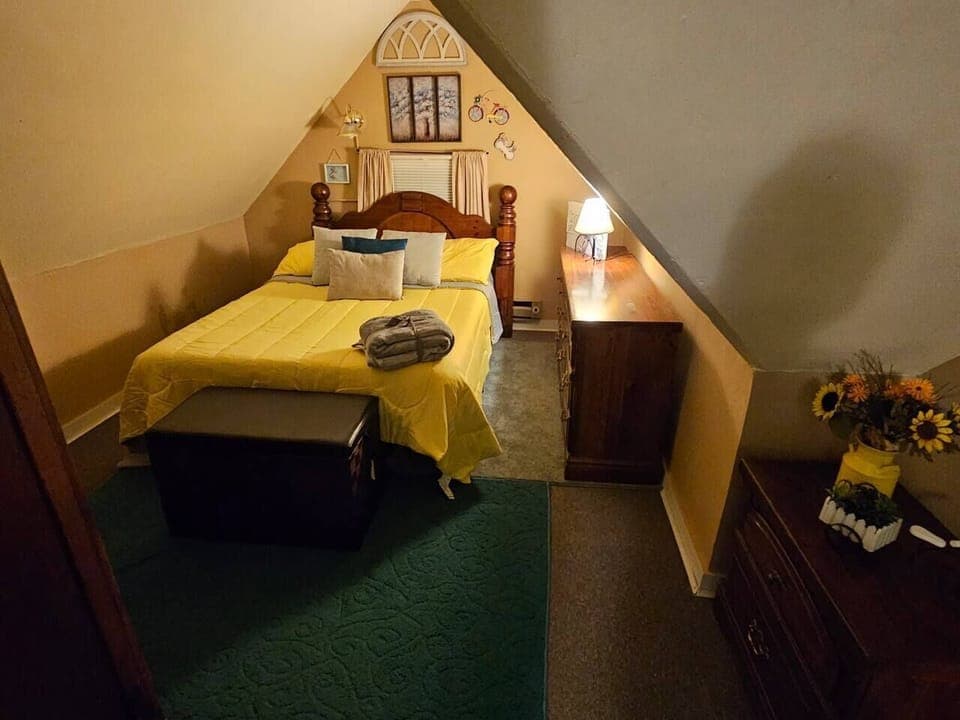 Cheery bedroom in cozy attic of centennial Queen Anne cottage. 