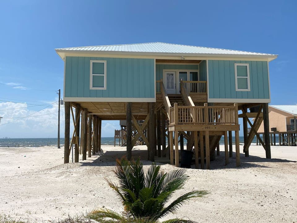 Beachfront property elevated on stilts with direct beach access and covered parking underneath.