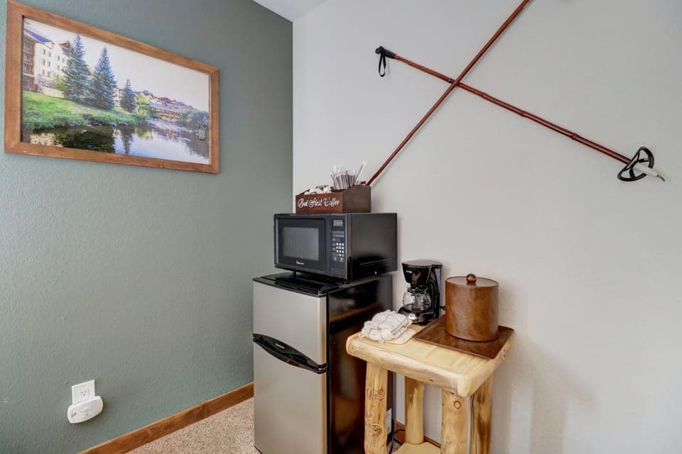 A small kitchen area with a mini fridge, microwave, and coffee station.