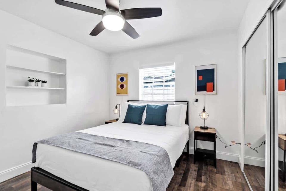 Sleep peacefully in this stylish bedroom with cozy bedding, built-in shelf, and modern art — perfect for winding down.