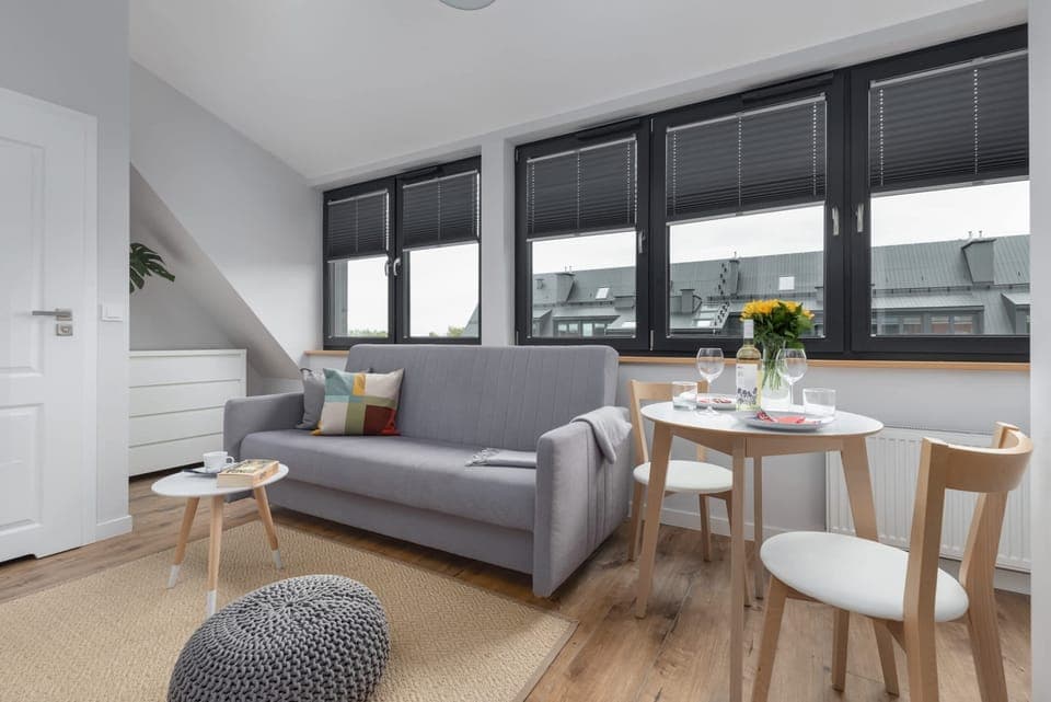 A modern living and dining area with large windows, a cozy sofa, and a stylish table setting.
