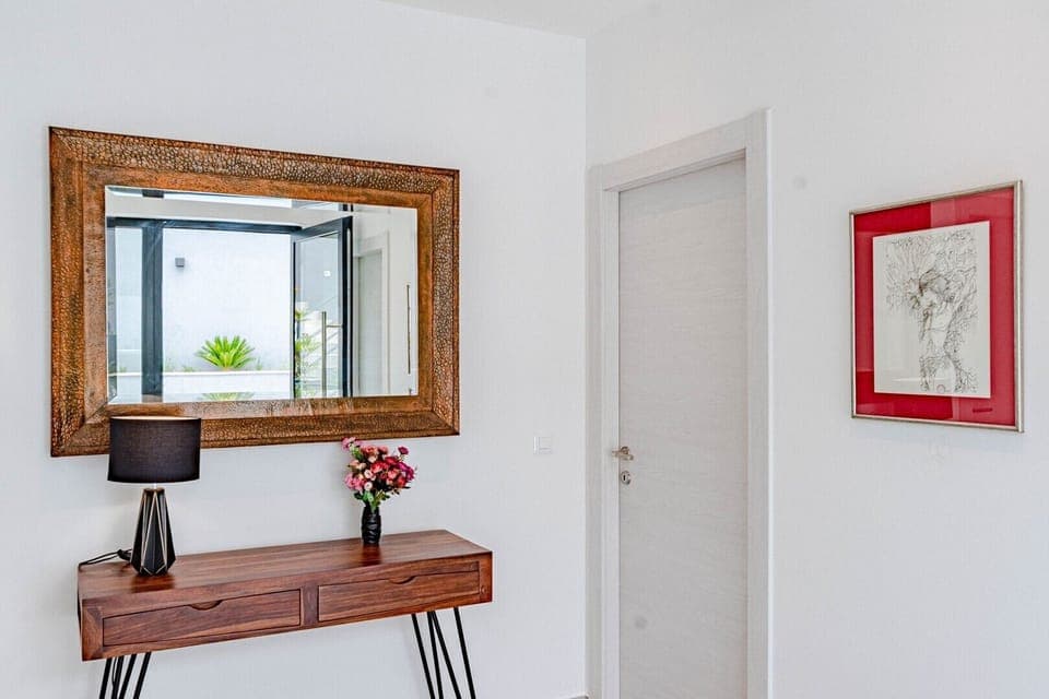 A painting, wooden table and a mirror on the first floor of the Dalmation luxury beachfront villa Miracul with a private pool and gym