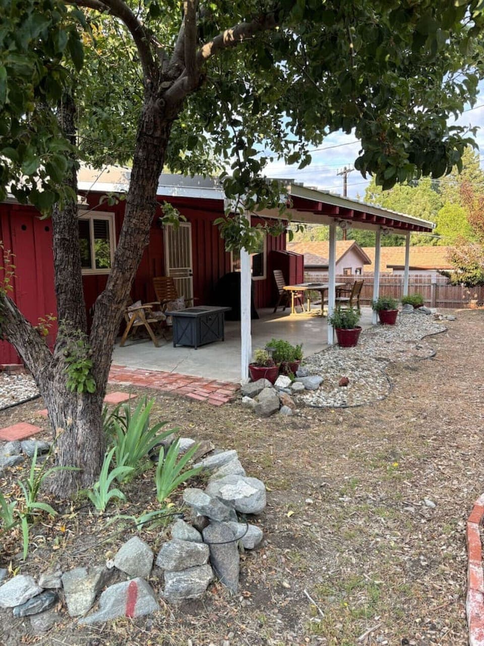 Relax on the shaded patio surrounded by trees, garden beds, and the calming feel of nature.