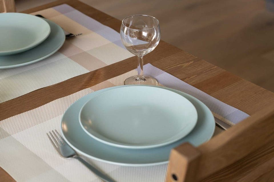 A close-up of the dining table set with elegant blue plates and a glass of wine.

