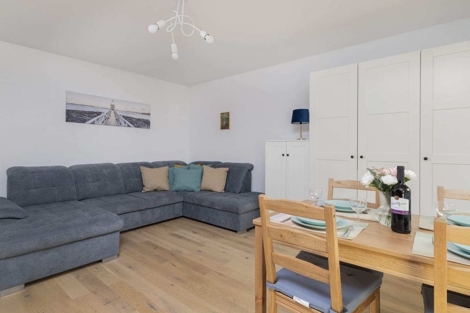 Another view of the living room showcasing the gray sofa and the dining area.
