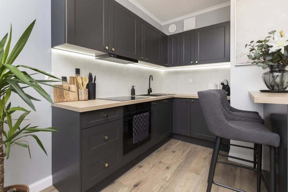 Kitchen with dark cabinets, dining area, and wooden countertop.
