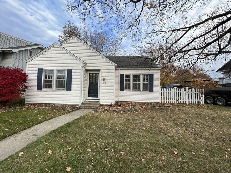 Front of the cottage with white picket fence on side yard. 