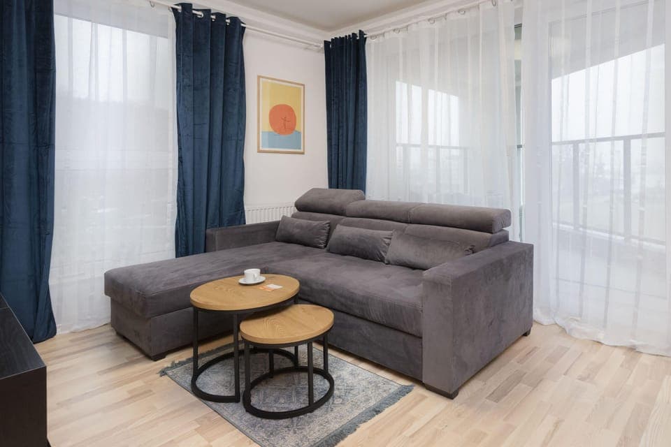 A cozy and modern living room with a gray sofa, wooden accents, and a coffee table, creating a comfortable ambiance.