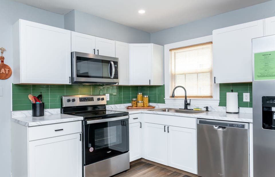 Bright white cabinetry and green tile backsplash add of pop of charm.